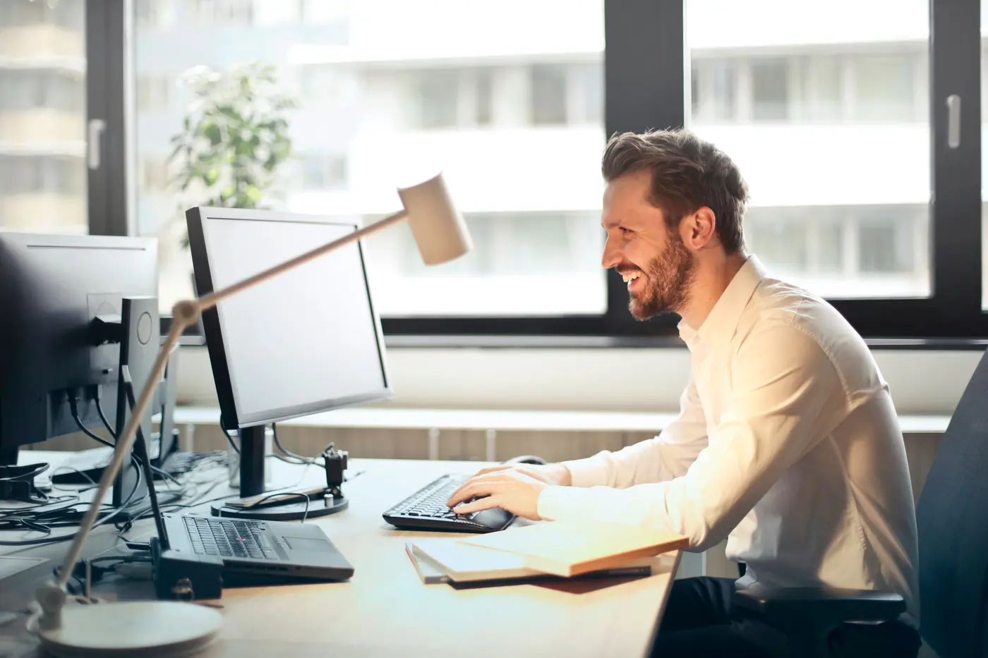 A back-office employee working through payroll on dual monitors